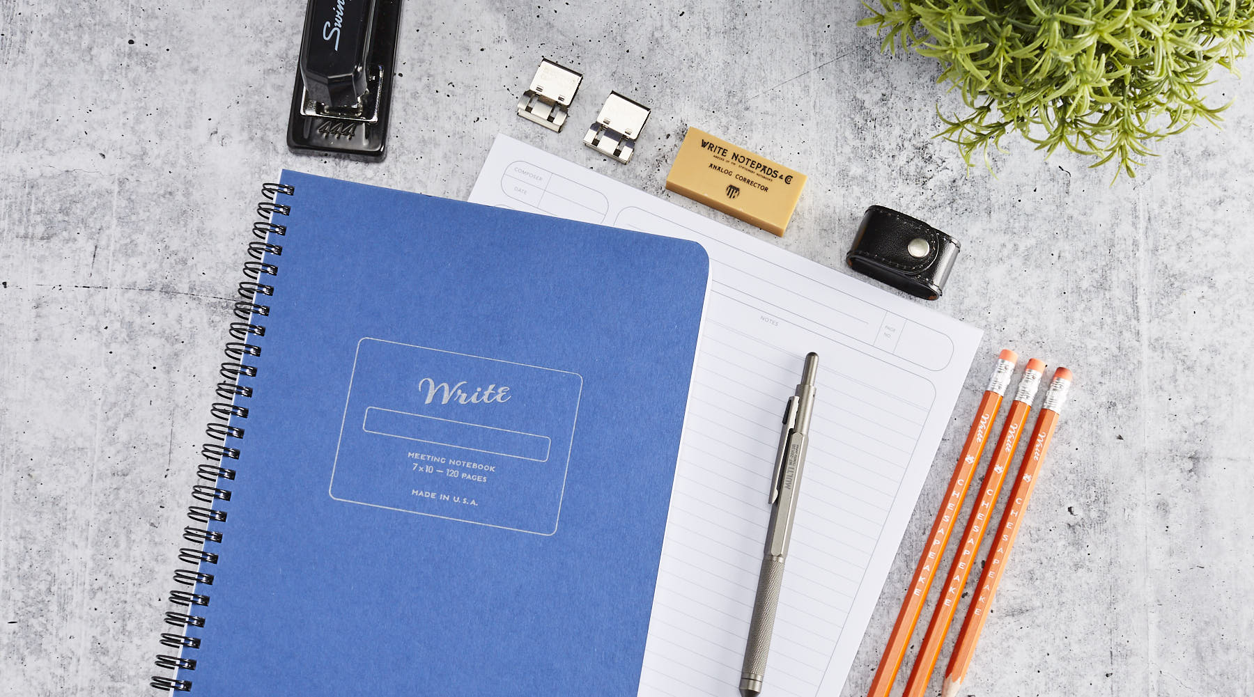 Blue Meeting Notebook on a desk with pencils and pens